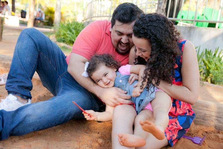  pai e mãe brincando com a filha no banco de areia durante ensaio de família no Parque Villa Lobos, Pinheiros, Zona Oeste, São Paulo