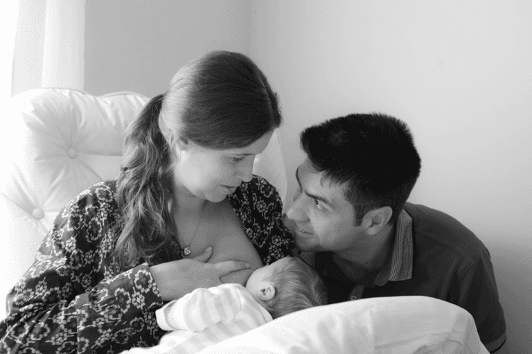 pai admirando mãe amamentando bebê recém nascido durante ensaio newborn lifestyle em residencia no Brooklyn, Zona Sul, São Paulo