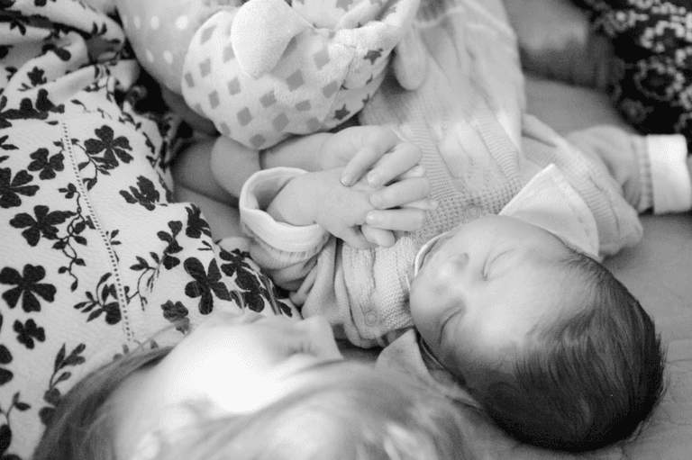 irmã mais velha segurando a mão de bebê recém nascido durante ensaio newborn lifestyle em residencia no Brooklyn, Zona Sul, São Paulo