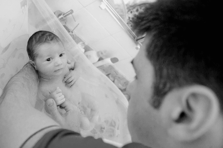 pai dando banho em bebê recém nascido durante ensaio newborn lifestyle em residencia no Brooklyn, Zona Sul, São Paulo