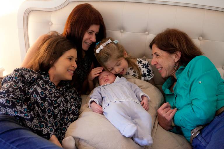 mãe, avós e irmãs admirando bebê recém nascido durante ensaio newborn lifestyle em residencia no Brooklyn, Zona Sul, São Paulo