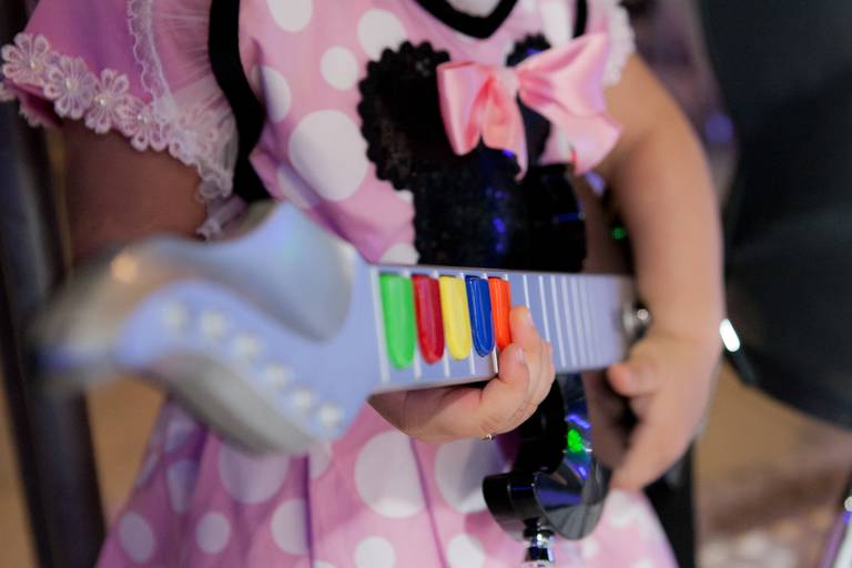 detalhe de menina tocando/brincando no guitar hero em seu aniversário de 3 anos da Minnie no Buffet Planeta Kids, Alto da Lapa, Zona Oeste, São Paulo.