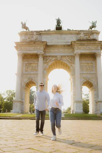 Casal correndo no Arco della pace centro histórico de milão em ensaio fotográfico