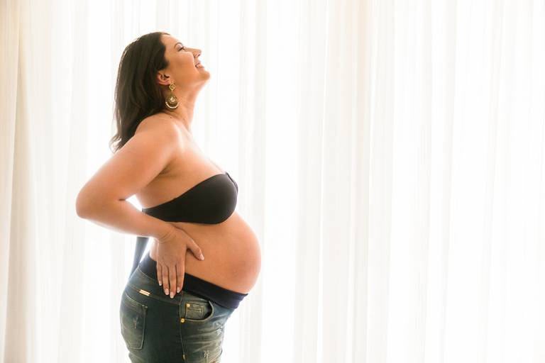 gestante na frente da janela do apartamento