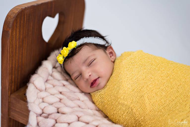 Book recém nascido de menina com amarelo e caminha de madeira