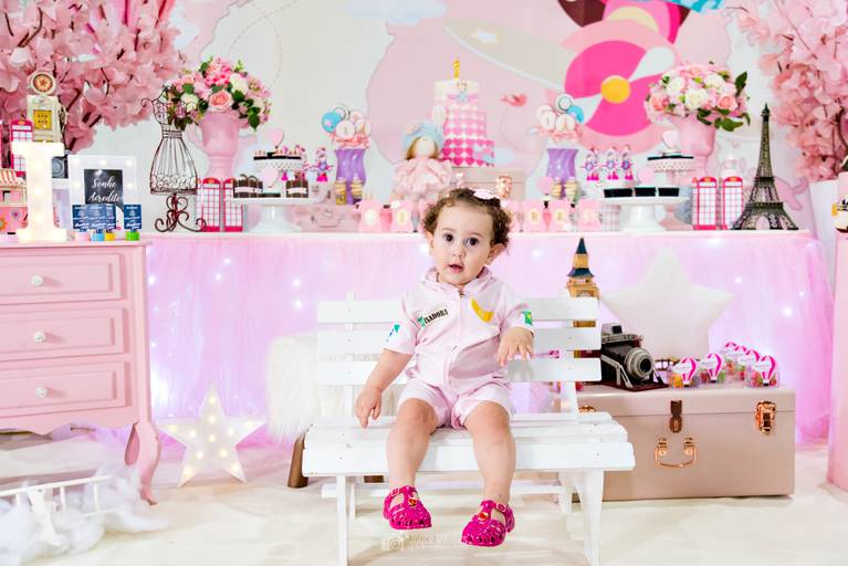 Aniversariante com roupa de aviadora em festa temática Volta ao Mundo cor de Rosa