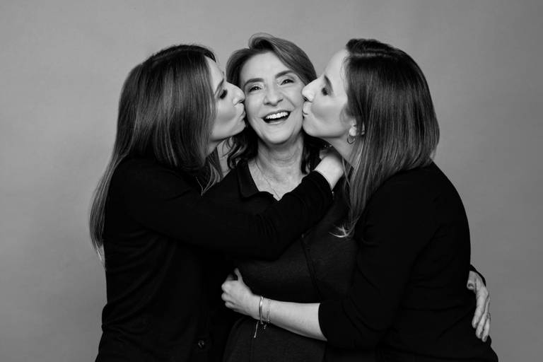 Mãe sendo beijada por duas filhas uma de cada lado foto em preto e branco

