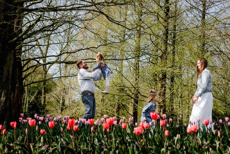 Parents playing with their children among tulip fields in Keukenhof, a favorite experience for travelers visiting the Netherlands in spring.