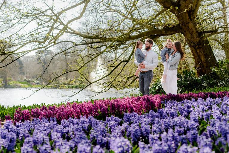 Family walking through colorful flower gardens in Keukenhof during their vacation photoshoot near Amsterdam.