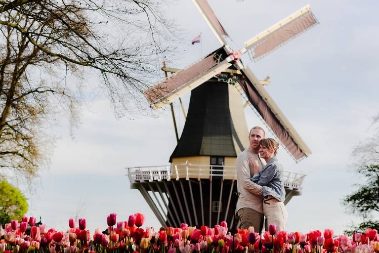 Couple embracing in front of the Keukenhof windmill, surrounded by spring tulips during a morning photoshoot.