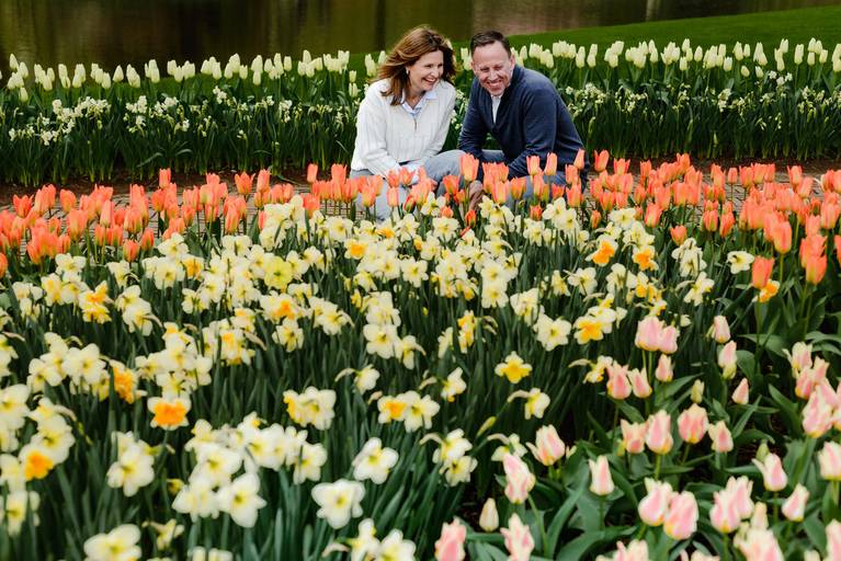 Candid couple enjoying a tulip garden photoshoot at Keukenhof, with vibrant spring flowers in front of them. Ideal for travelers looking for things to do near Amsterdam, like booking a vacation photographer.