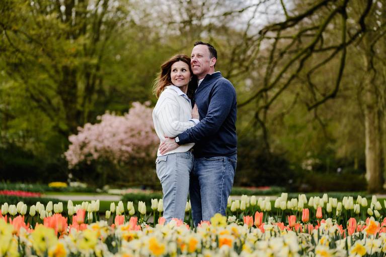 Couple embracing during a spring photoshoot at Keukenhof Gardens, surrounded by blooming tulips and daffodils. A popular day trip for travelers visiting the Netherlands who want romantic photos near Amsterdam
