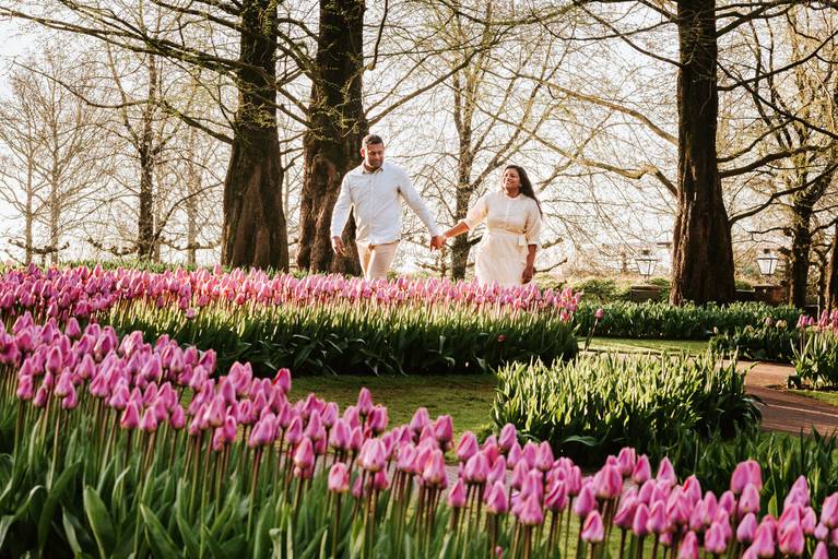 Couple photoshoot of a couple walking through pink tulips in Keukenhof Gardens at golden hour, perfect for travelers on Netherlands river cruises in spring