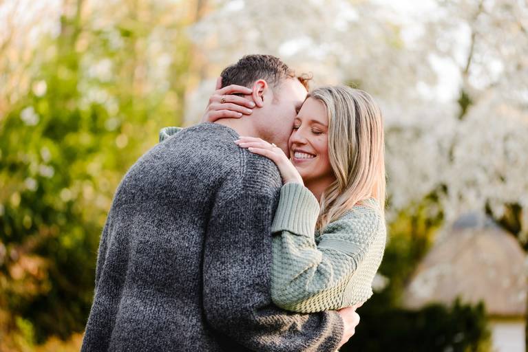 Couple embracing after a surprise proposal in Keukenhof, surrounded by soft spring blossoms. She smiles while showing her ring. Shot by a Keukenhof proposal photographer who helps choose private, romantic locations in the gardens.
