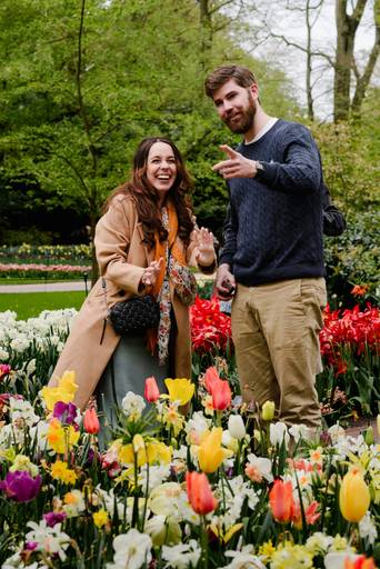 Newly engaged couple laughing together in Keukenhof right after the proposal. They stand among colourful tulips in an area selected for privacy, showing the candid joy of a real surprise moment.