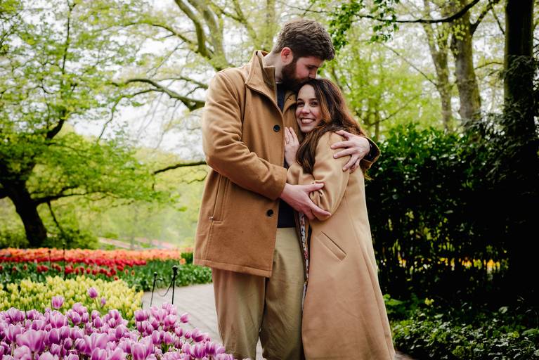 Couple embracing after their surprise proposal in Keukenhof, surrounded by soft pink and purple tulips. Photographed in a calm area of the garden to keep the moment personal and uninterrupted.