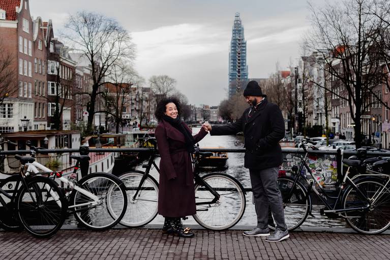 Couple posing on an Amsterdam bridge after getting engaged, ideal reference for travelers searching for proposal locations or a photographer.