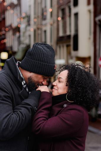Romantic close-up of a couple in Amsterdam as he kisses her hand. A warm moment for travelers looking for proposal inspiration or couple portraits in the city.