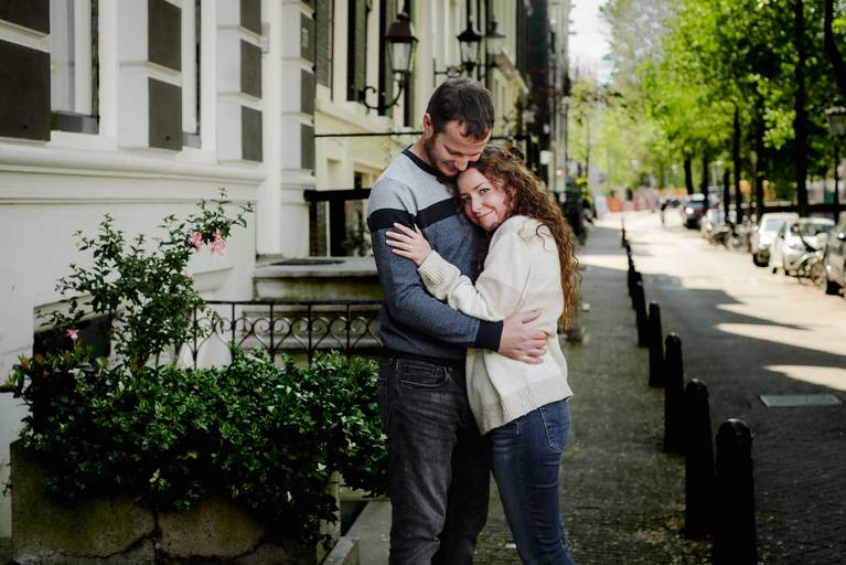 Newly engaged couple embracing on a calm Amsterdam street, enjoying a quiet moment together.