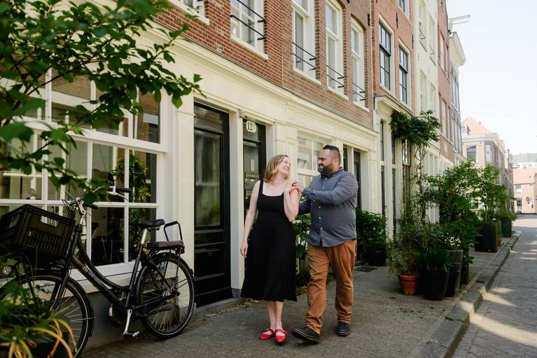 Couple walking through a charming Amsterdam street lined with bikes and greenery during their engagement session.