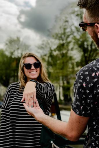 Woman showing her engagement ring with a big smile during a surprise proposal session in Amsterdam.