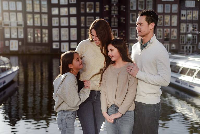 Relaxed family moment captured during a vacation photo session in Amsterdam, with parents and children standing together by the canal.