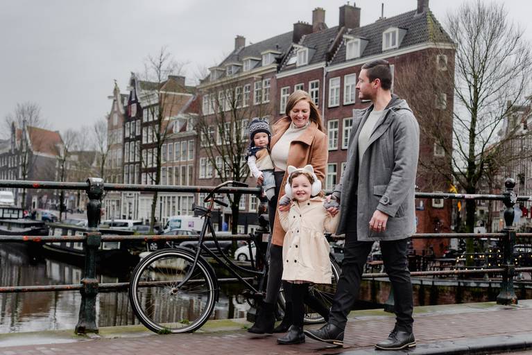 Winter family vacation photography in Amsterdam, capturing parents and children near a canal and bicycles.