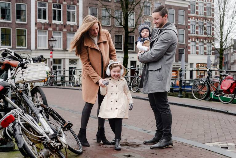 Parents and young children enjoying a casual family photo session in Amsterdam, surrounded by bicycles and canal houses.