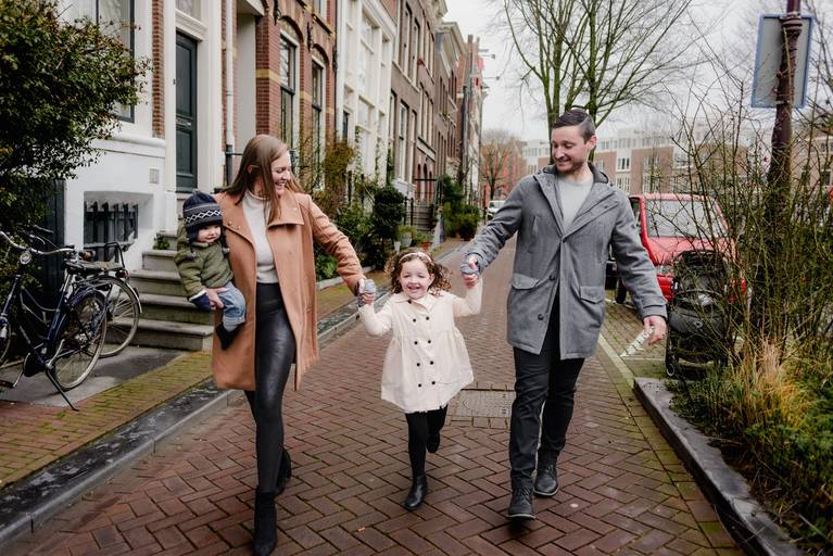 Family walking hand in hand through a quiet Amsterdam street during a relaxed vacation photography session.