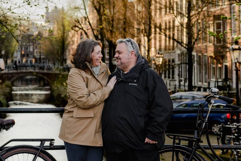 Couple enjoying a quiet moment on an Amsterdam bridge at sunset, a favorite spot for travel photography in the city.
