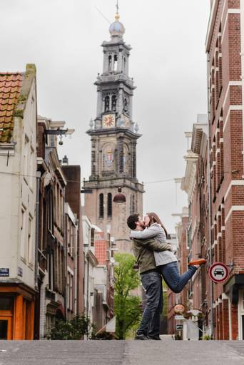 Couple sharing a kiss with the Westerkerk tower in the background, one of Amsterdam’s most iconic landmarks.