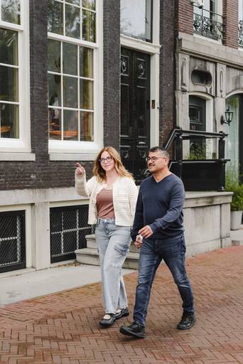 Couple exploring an Amsterdam neighborhood, pointing at the buildings during their photoshoot.