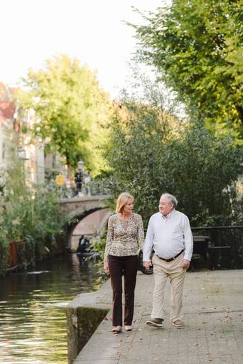Couple walking hand in hand along a quiet Amsterdam canal during their photo session