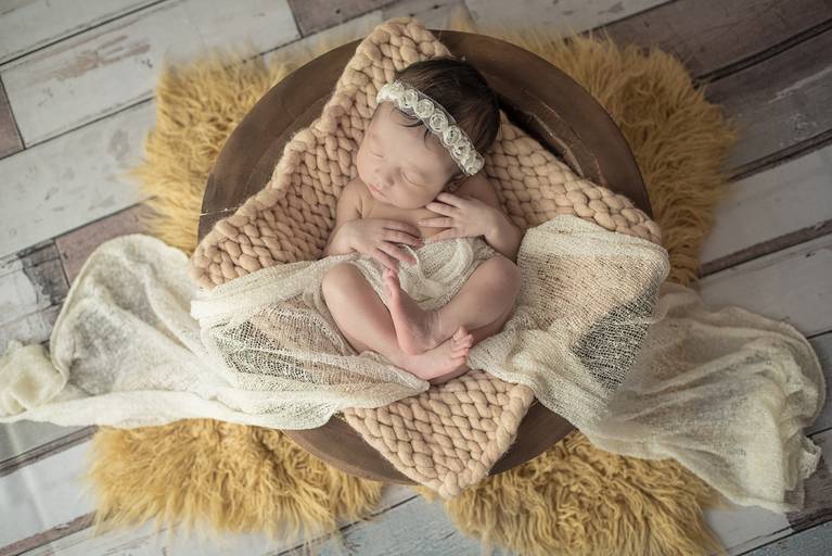 bebê Newborn deitado de barriga pra cima em cesto