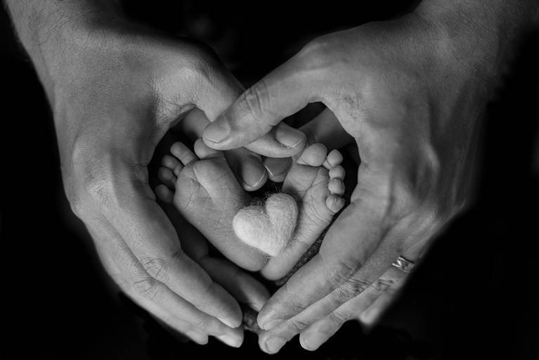 pés do bebê dentro das mãos dos pais com coração