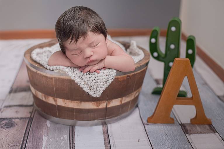 bebê Newborn em cesto e cenário com inicial do nome