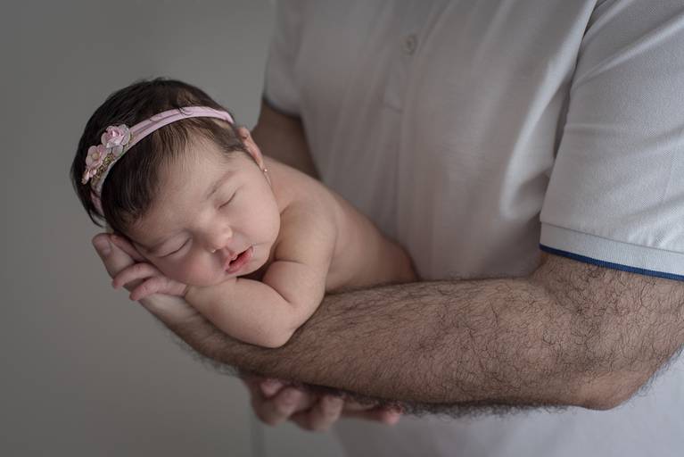 Newborn deitado nas mãos do pai