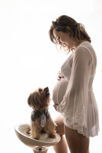 Gestante com vestido branco de frente com seu cachorro