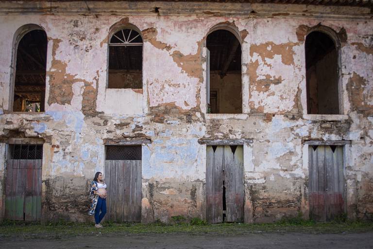 Gestante em frente a ruínas de casarão antigo