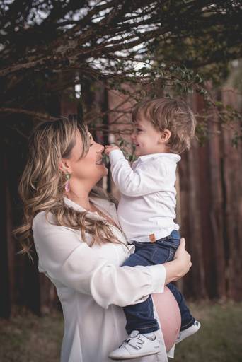 gestante segura o filho mais velho no colo sorrindo