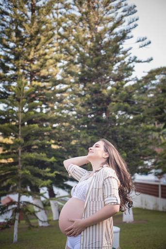 Gestante mexendo no cabelo em no meio as árvores