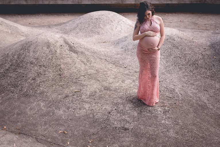 gestante vestida com conjunto rosa em meio a morro de cimento