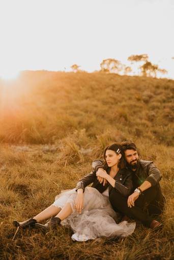 noivos abraçados curtindo o pôr do sol no alto de uma montanha. 