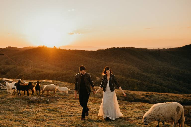 Noivos em ensaio pré casamento no alto da montanha, com ovelhas e um lindo pôr do sol.