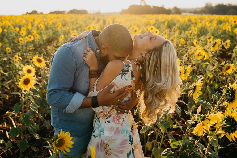 Noivos em ensaio pré-wedding  se abraçando no campo de girassol no pôr do sol.