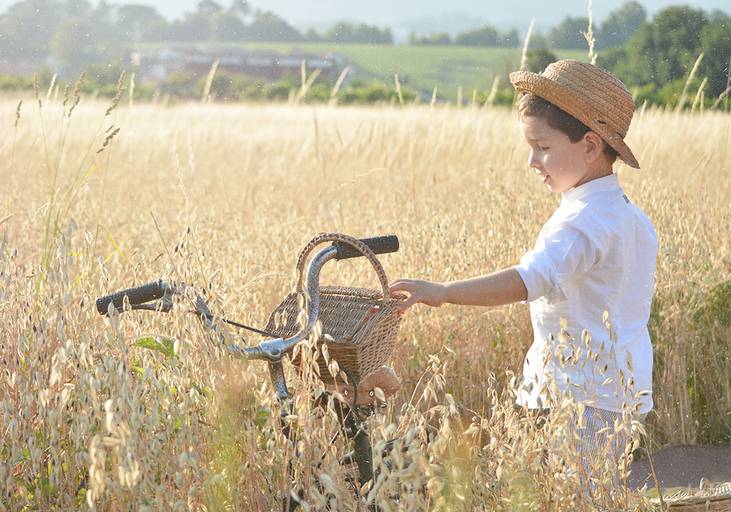 sessão menino bicicleta com chapéu de palha campo de trigo