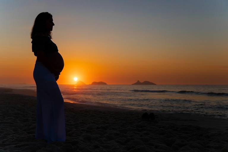 Silhueta de gestante no nascer do sol na Praia da Barra, Rio de Janeiro.