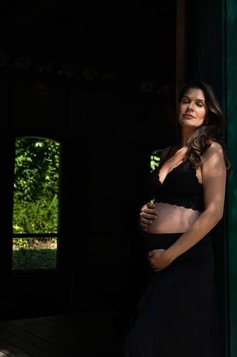 Foto artística da barriga de gestante iluminada por luz natural.