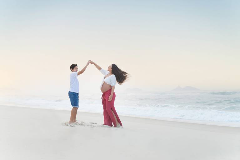 casal de gestantes dançando na areia da praia da Barra no nascer do sol.