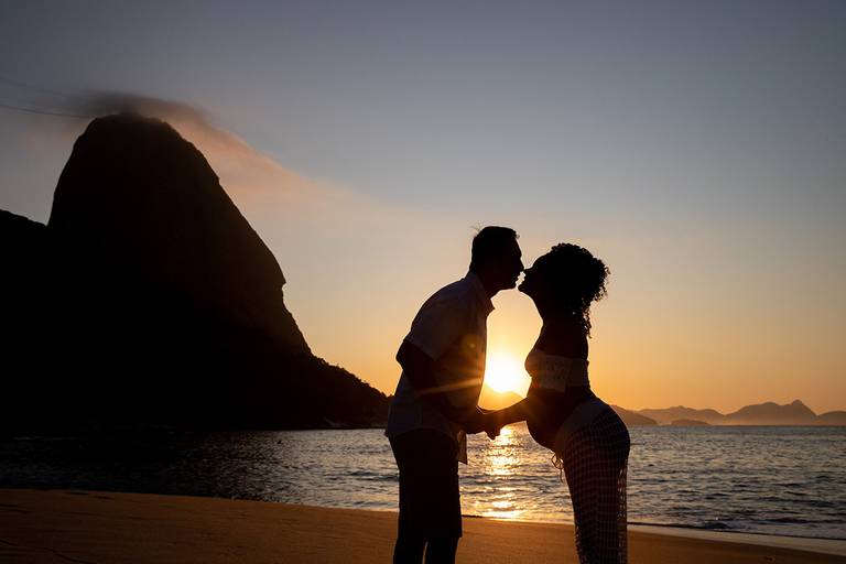 Silhueta de casal de gestantes na Praia Vermelha com o Pão de Açúcar ao Fundo.